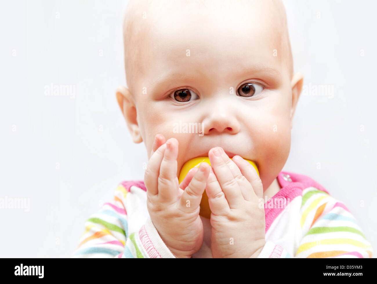 kleines Baby kaut auf einem hölzernen Apple-Spielzeug Stockfoto