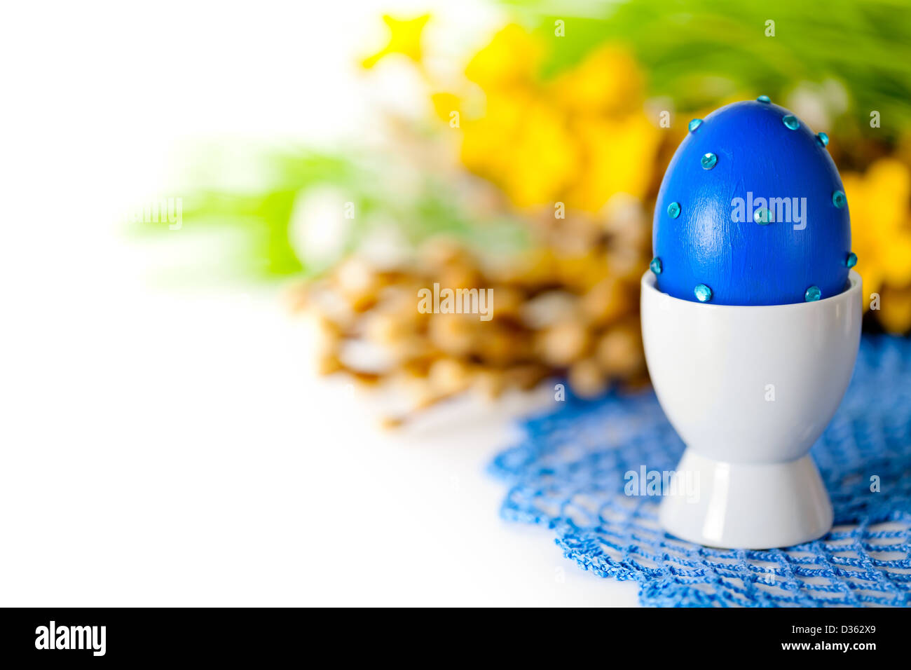 Ostern-Komposition mit blau Ei, Kätzchen und Frühlingsblumen auf gehäkelte Deckchen auf weißem Hintergrund. Ei, bemalt, dekoriert hand Stockfoto