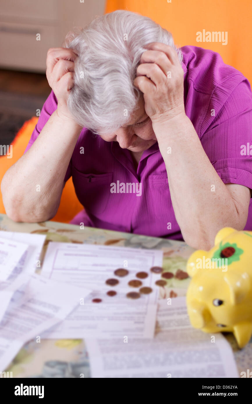Ältere Frau sitzt vor Papiere und verzweifelt Stockfoto