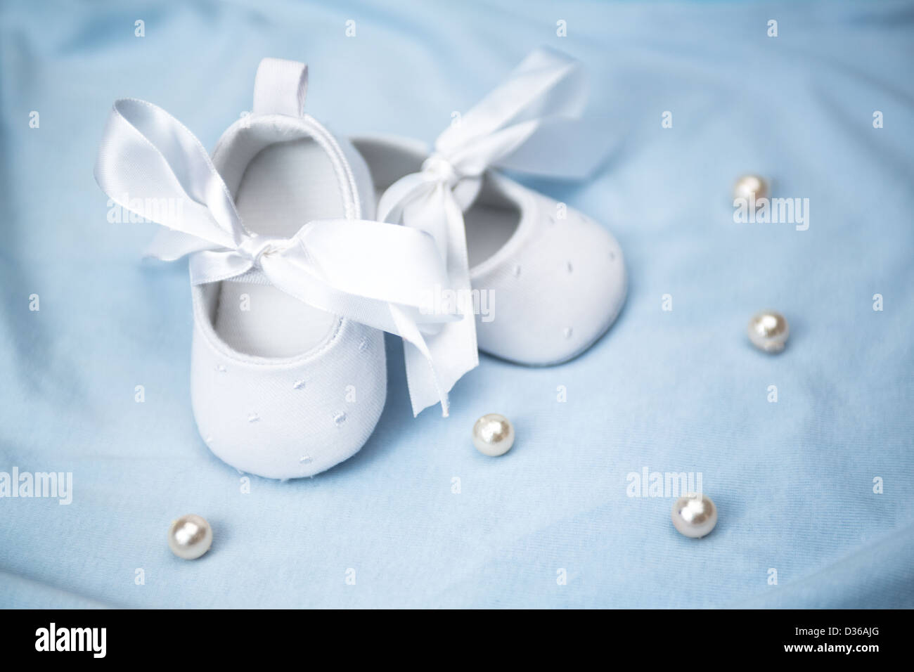 Weiße Babyschuhe auf blaue Decke Stockfoto