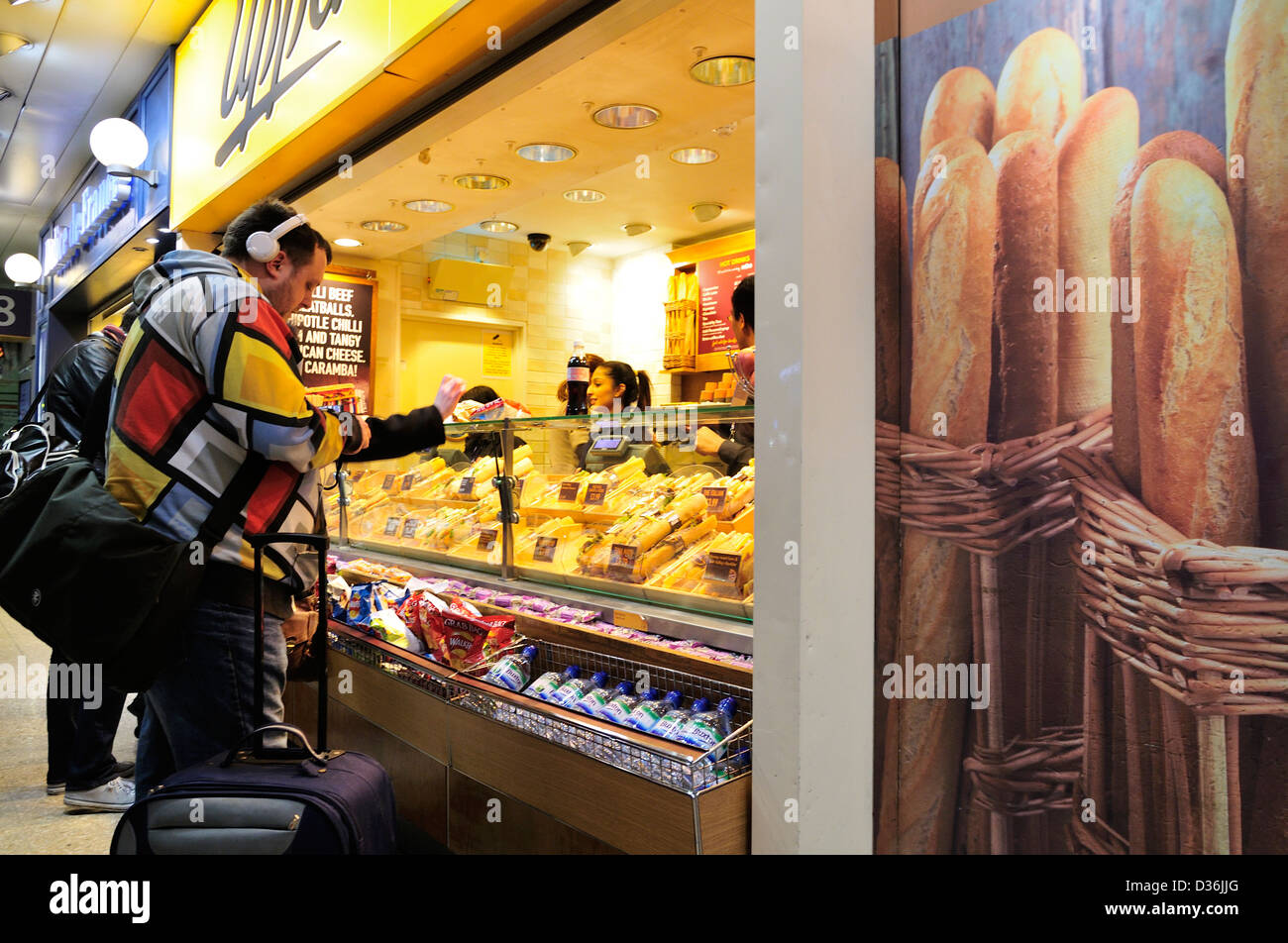 Mann ein Oberkruste Shop Outlet auf einer Eisenbahn Bahnhofshalle eine Baguette auswählen Stockfoto