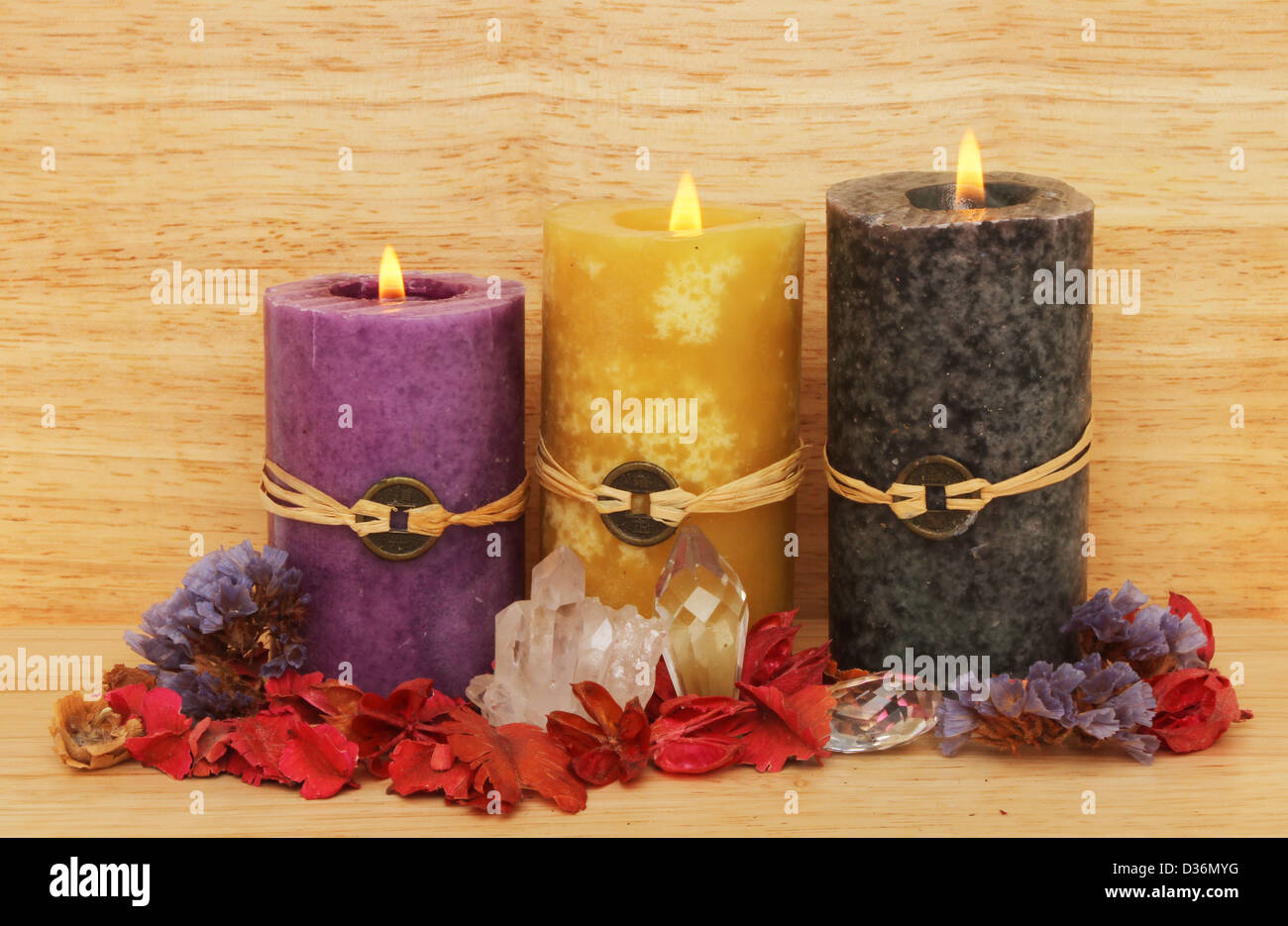 Drei brennende Feng Shui Kerzen, Kristalle und Potpourri auf einem hölzernen Hintergrund Stockfoto