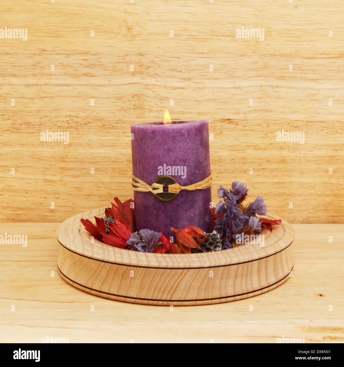 Brennende lila Feng Shui Kerze mit Potpourri in einer Holzschale Stockfoto