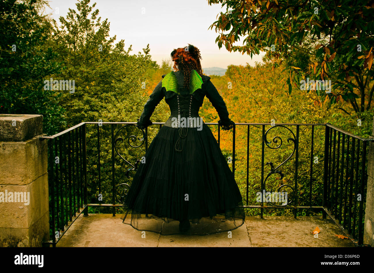Gothic Mädchen trägt grüne Fee Flügel mit Blick auf herbstliche Holz Stockfoto
