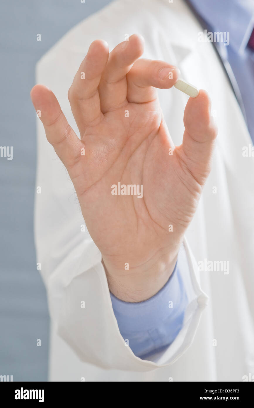 Männlichen Arzt hält eine Pille Nahaufnahme Bild mit geringer Tiefe von eingereicht mit Fokus auf Seite mit einer Kur. Stockfoto