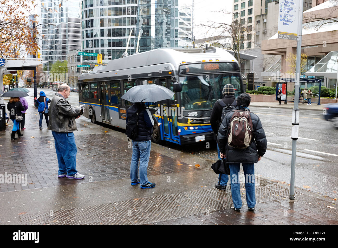 Menschen stehen im Regen warten auf einen Bus am Burrard street downtown Vancouver BC Kanada Stockfoto