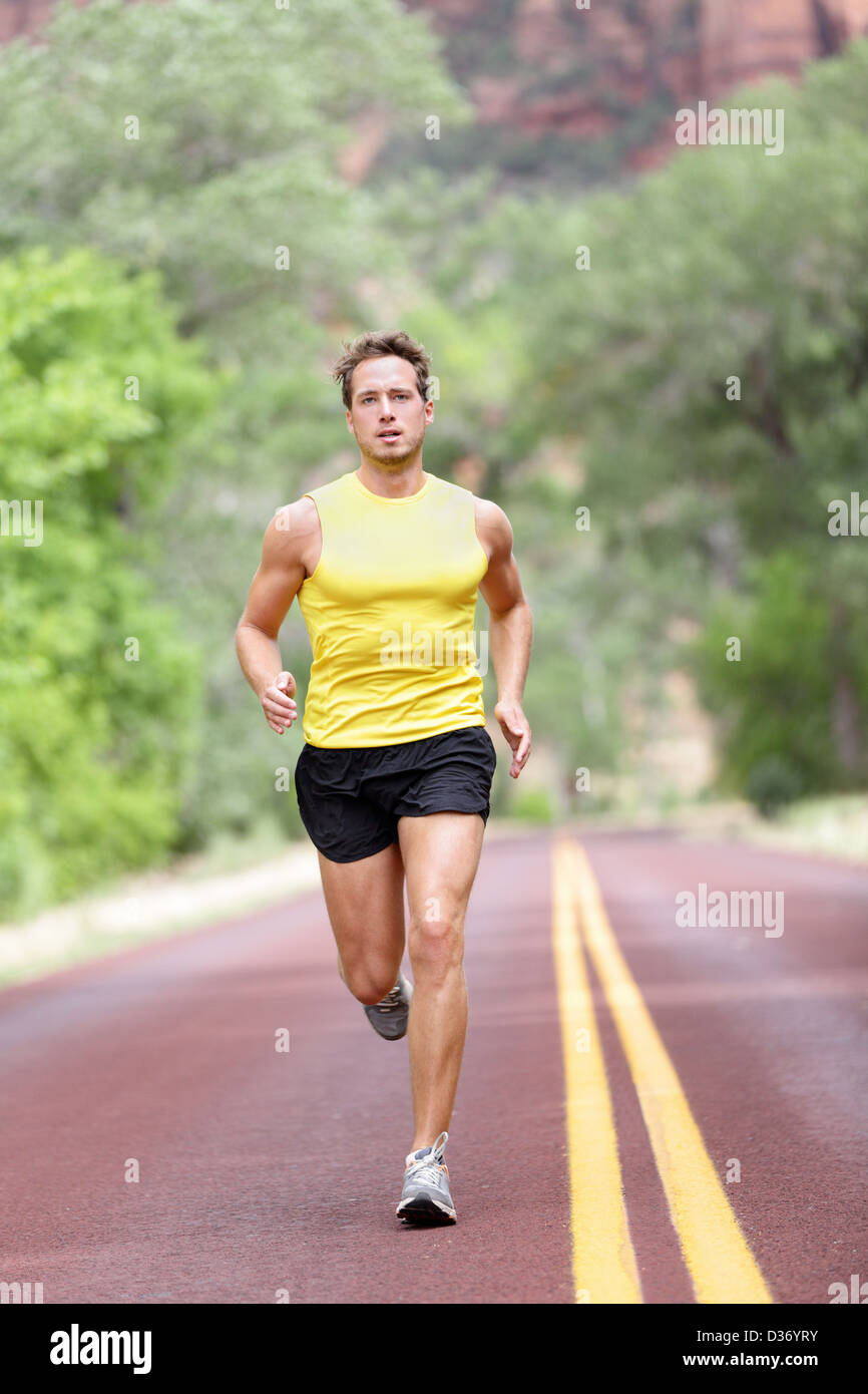 Gesamte Länge der Mann läuft mit Konzentration, Entschlossenheit und Stärke auf Straße Stockfoto