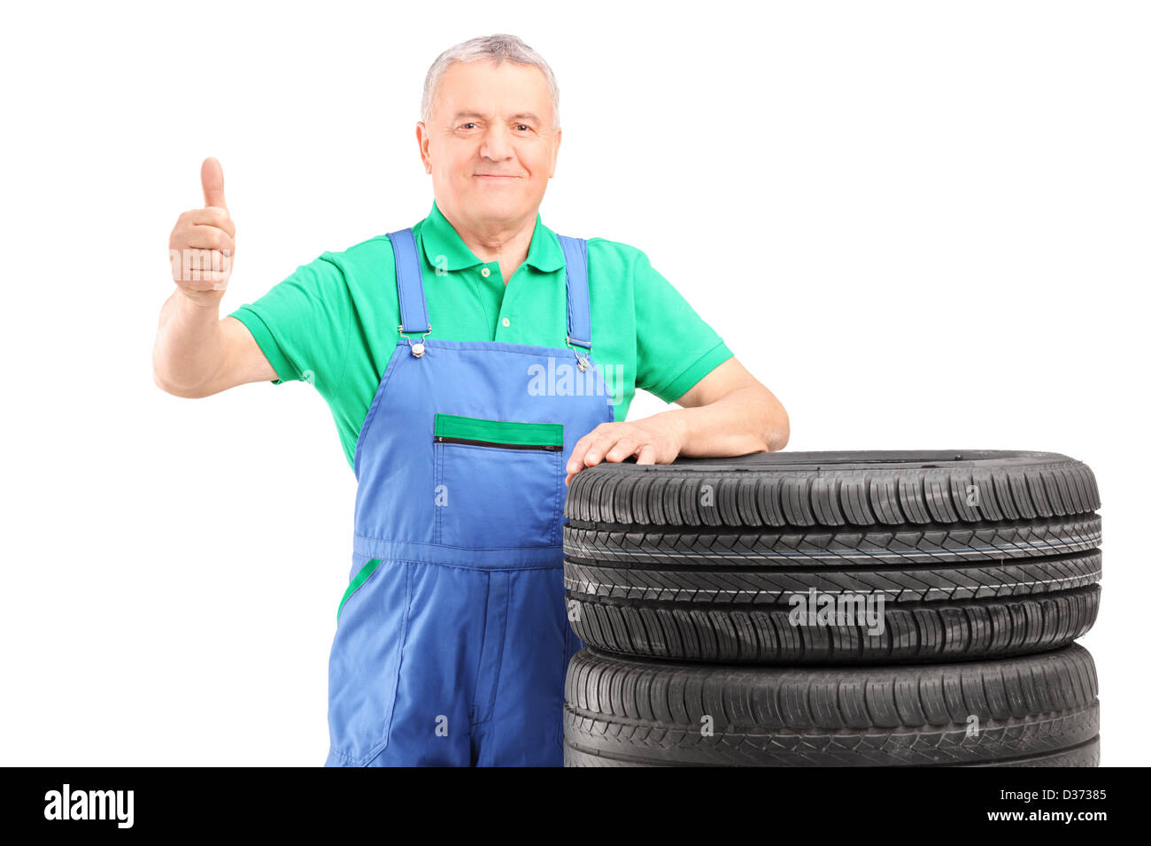 Ältere Arbeitnehmer posiert auf Pkw-Reifen und Daumen aufgeben isoliert auf weißem Hintergrund Stockfoto