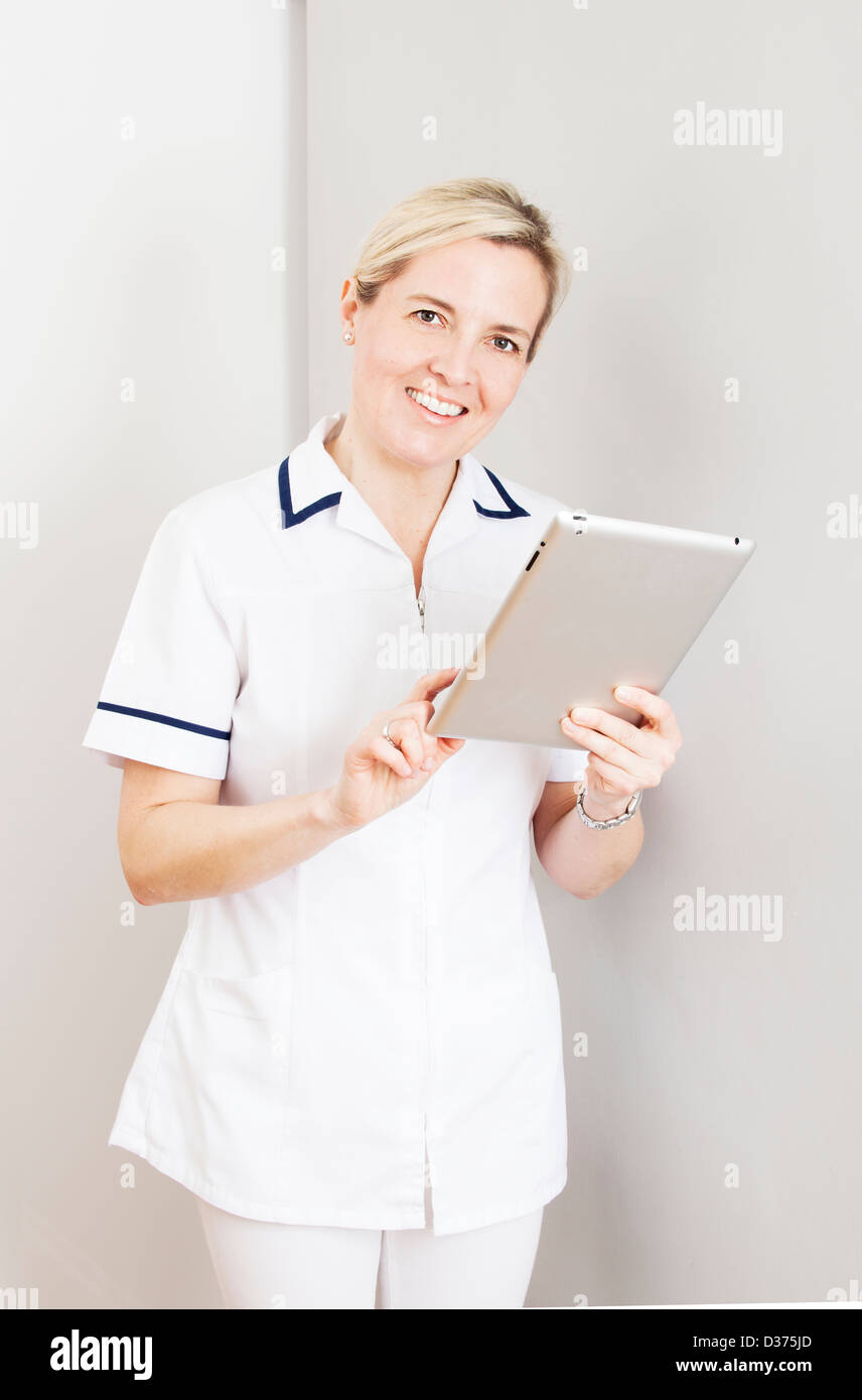 Lächelnd, weibliche tragen eine weiße medizinische Uniform hält eine digitale-Tablette. Stockfoto