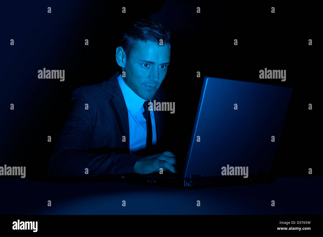 Ein Mann arbeitet auf einem Laptopcomputer in der Dunkelheit Stockfoto
