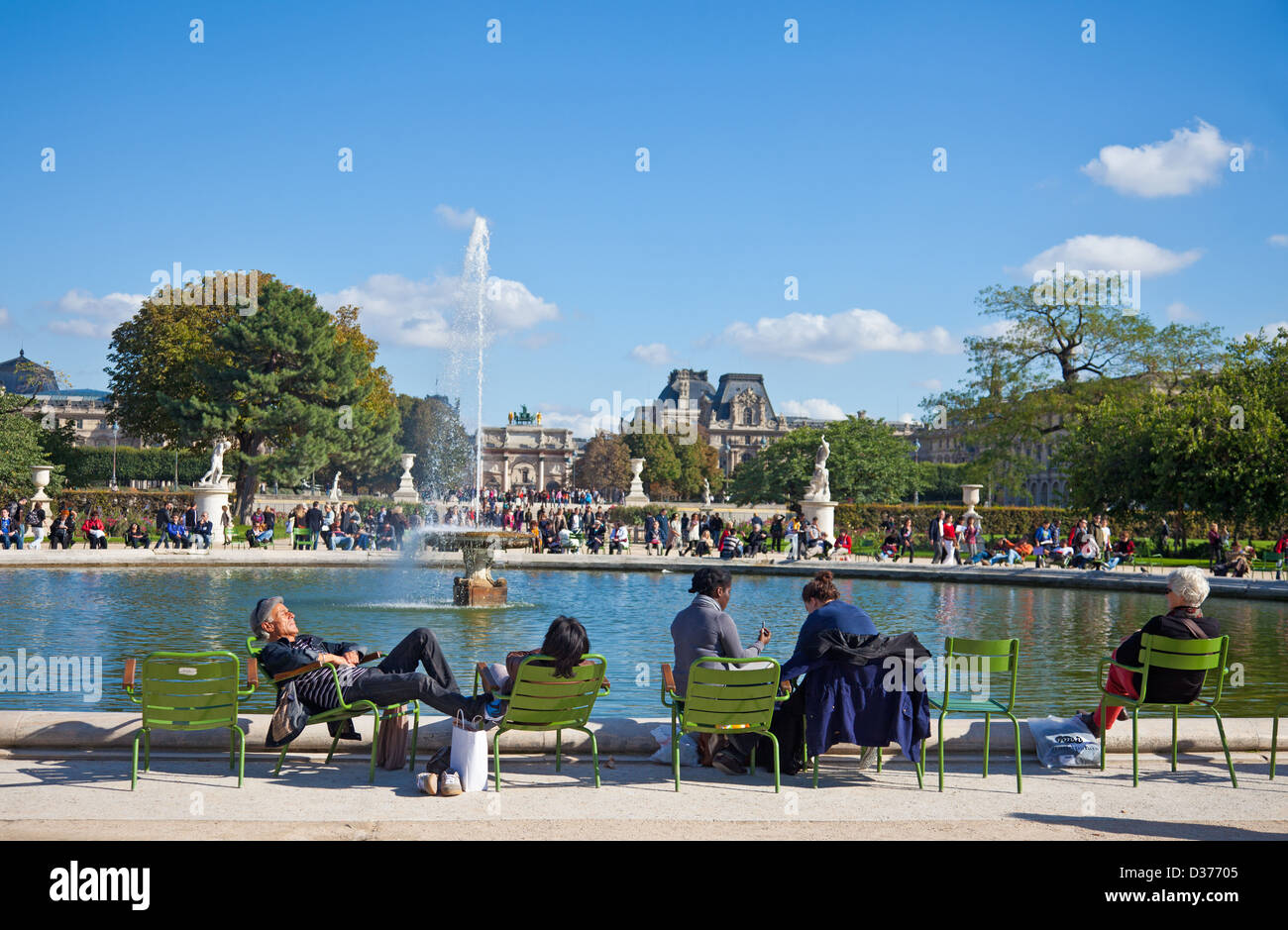 Menschen, die genießen einige Herbstsonne am Rand eines Teiches: Jardin des Tuileries, Paris. Louvre-Museum im Hintergrund. Stockfoto