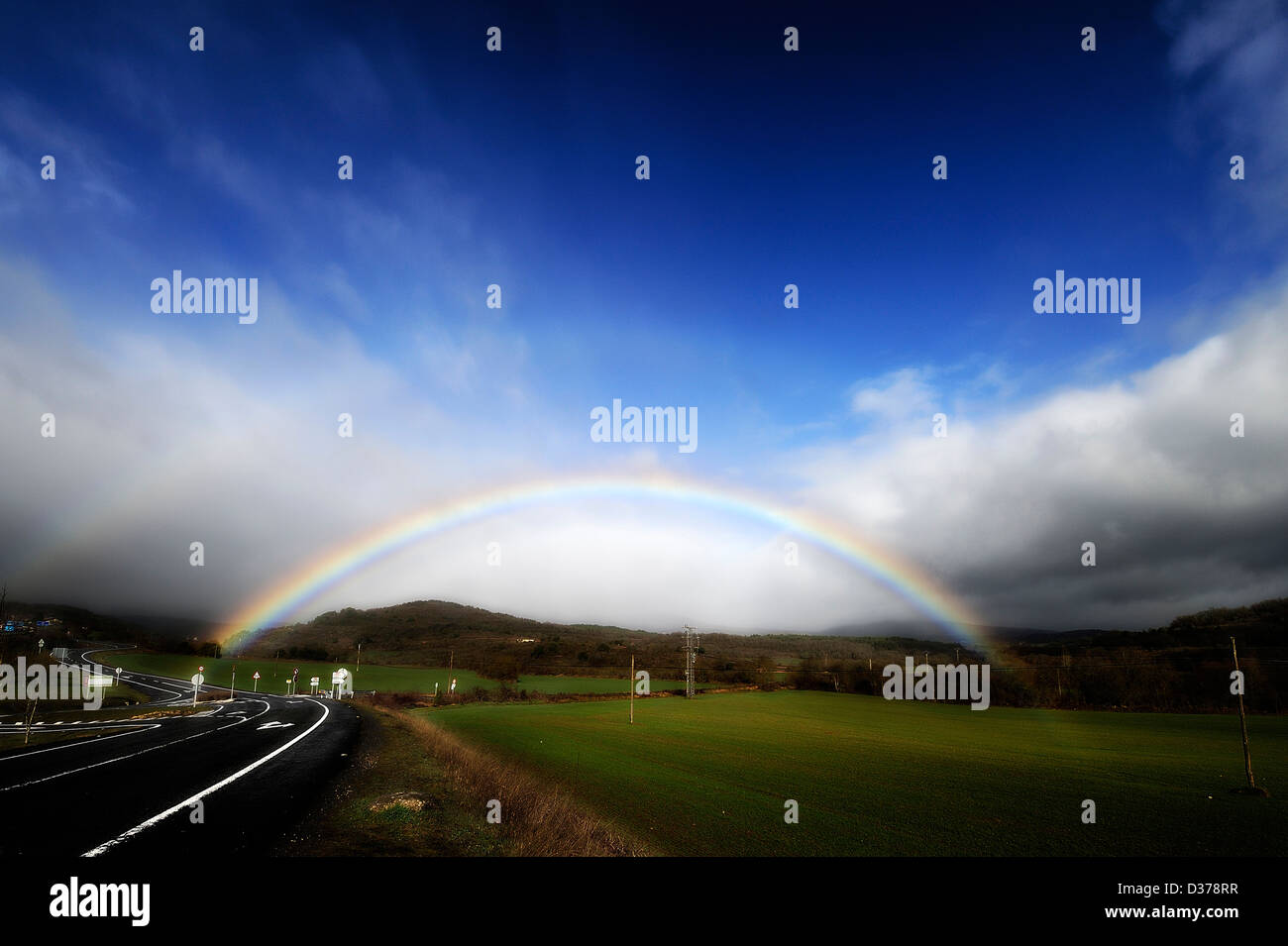 Regenbogen über Feld und Straße Stockfoto