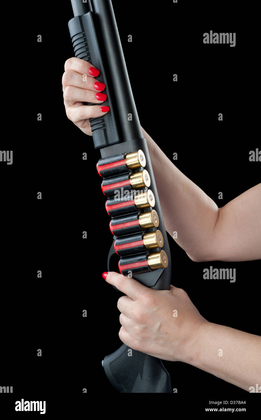 Eine Frau mit roten Fingernägeln hält auf einer 12 Gage Schrotflinte mit Clips von Munition. Stockfoto
