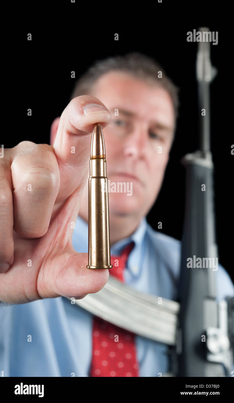 Ein Geschäftsmann in einem Kleid Hemd und Krawatte zeigt sich eine große 223 Kugel für seine Sturmgewehr. Stockfoto
