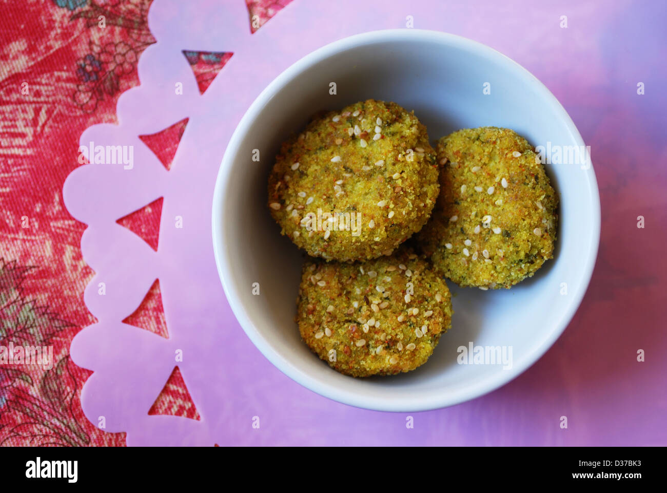 Drei Hirse vegetarische Frikadellen in eine kleine violette China Schüssel, rosa Herzen im Hintergrund Stockfoto