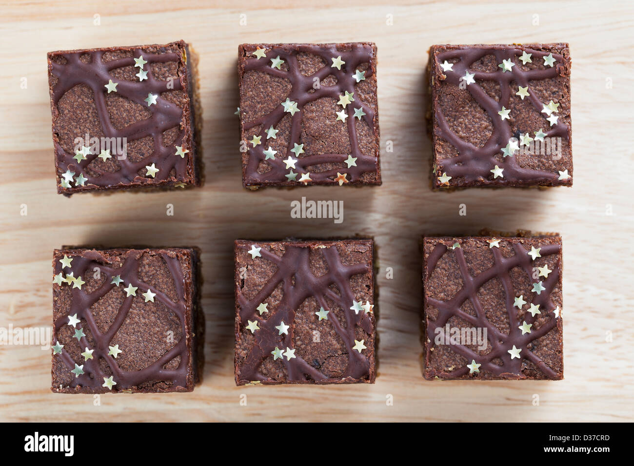 Sechs Schokoladen-Brownies, bestreut mit silbernen Sternen direkt von oben Stockfoto