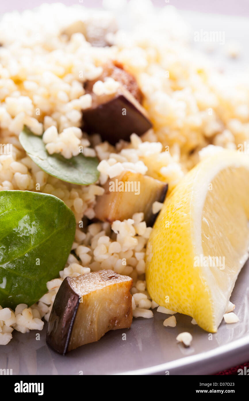 Bulgur-Salat mit Spinat gebratene Auberginen und eine Zitronenscheibe Stockfoto