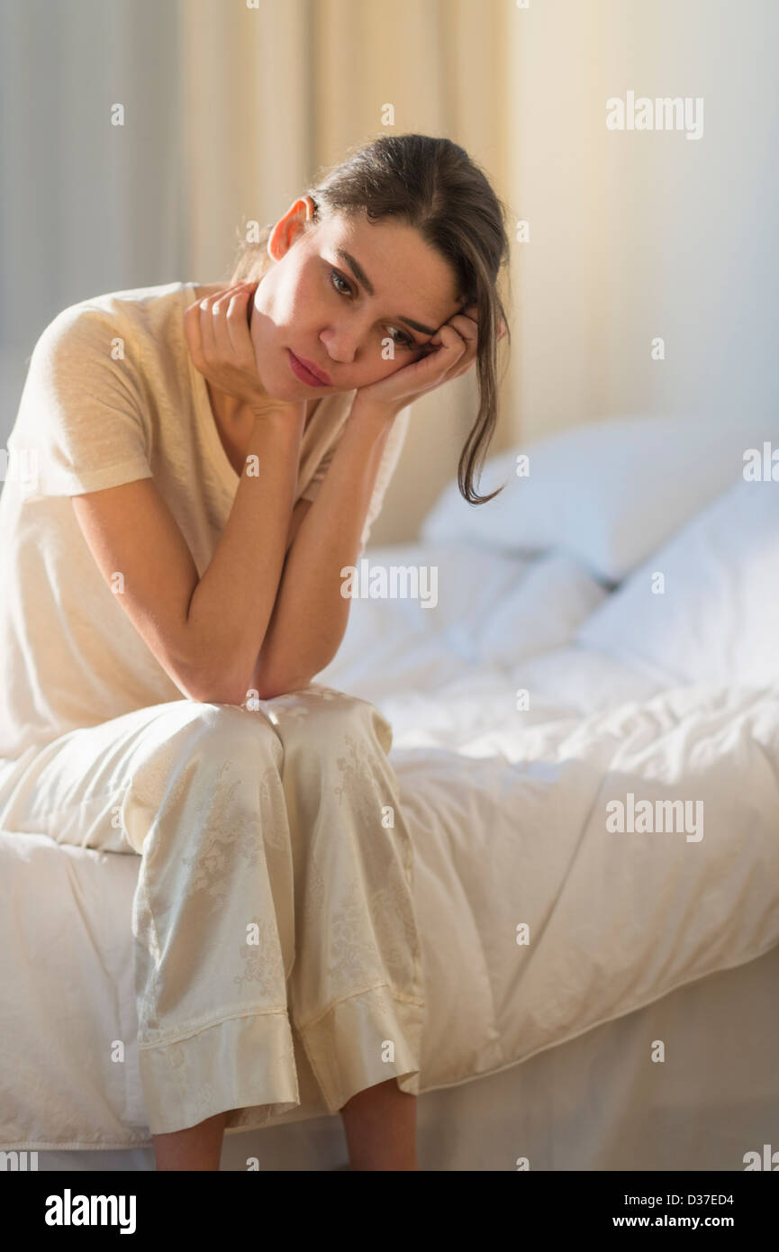 USA, New Jersey, Jersey City, junge Frau sitzt auf dem Bett mit Kopfschmerzen Stockfoto