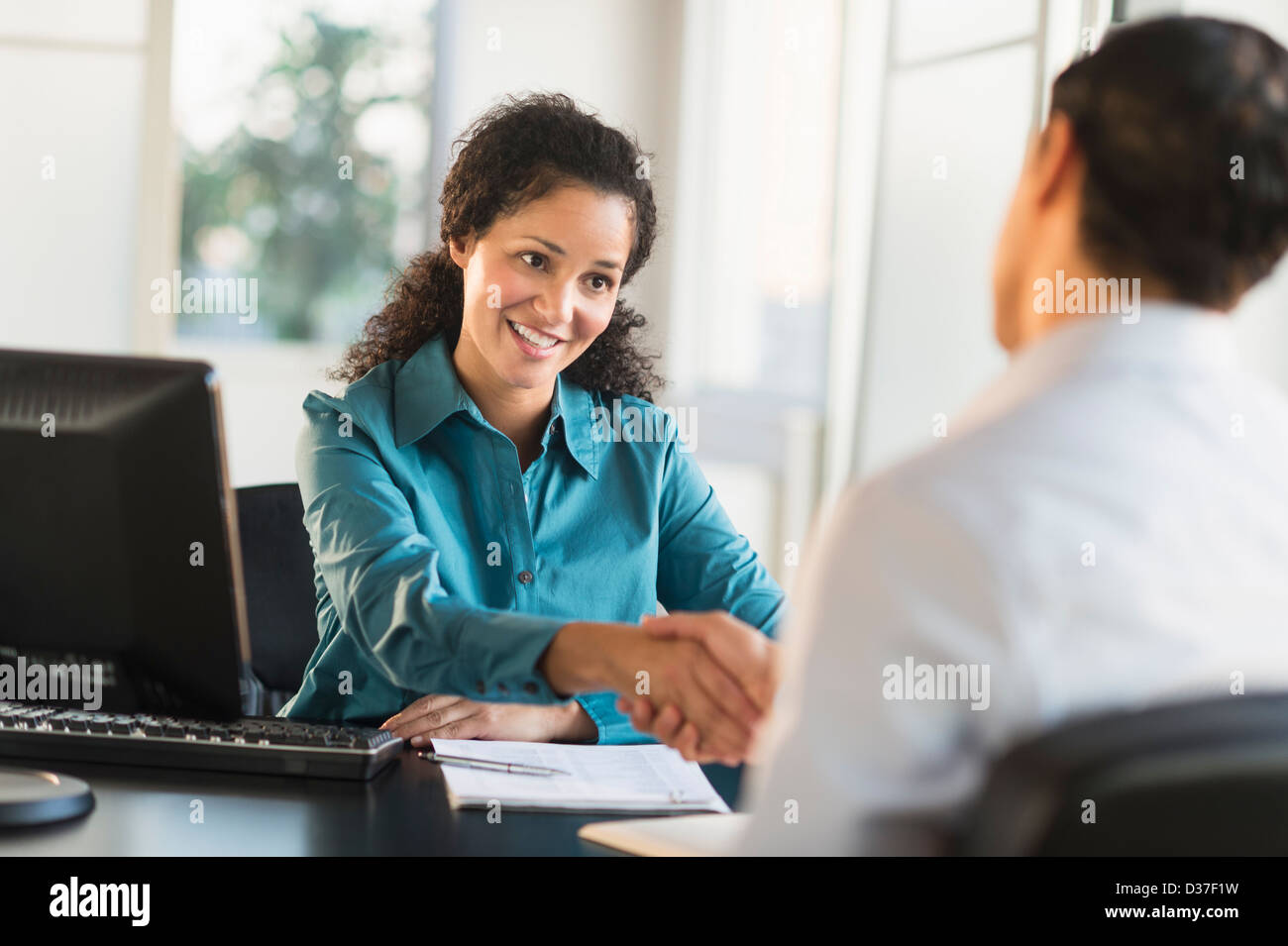 USA, New Jersey, Jersey City, Frau Hand mit Mann am Schreibtisch zu schütteln Stockfoto