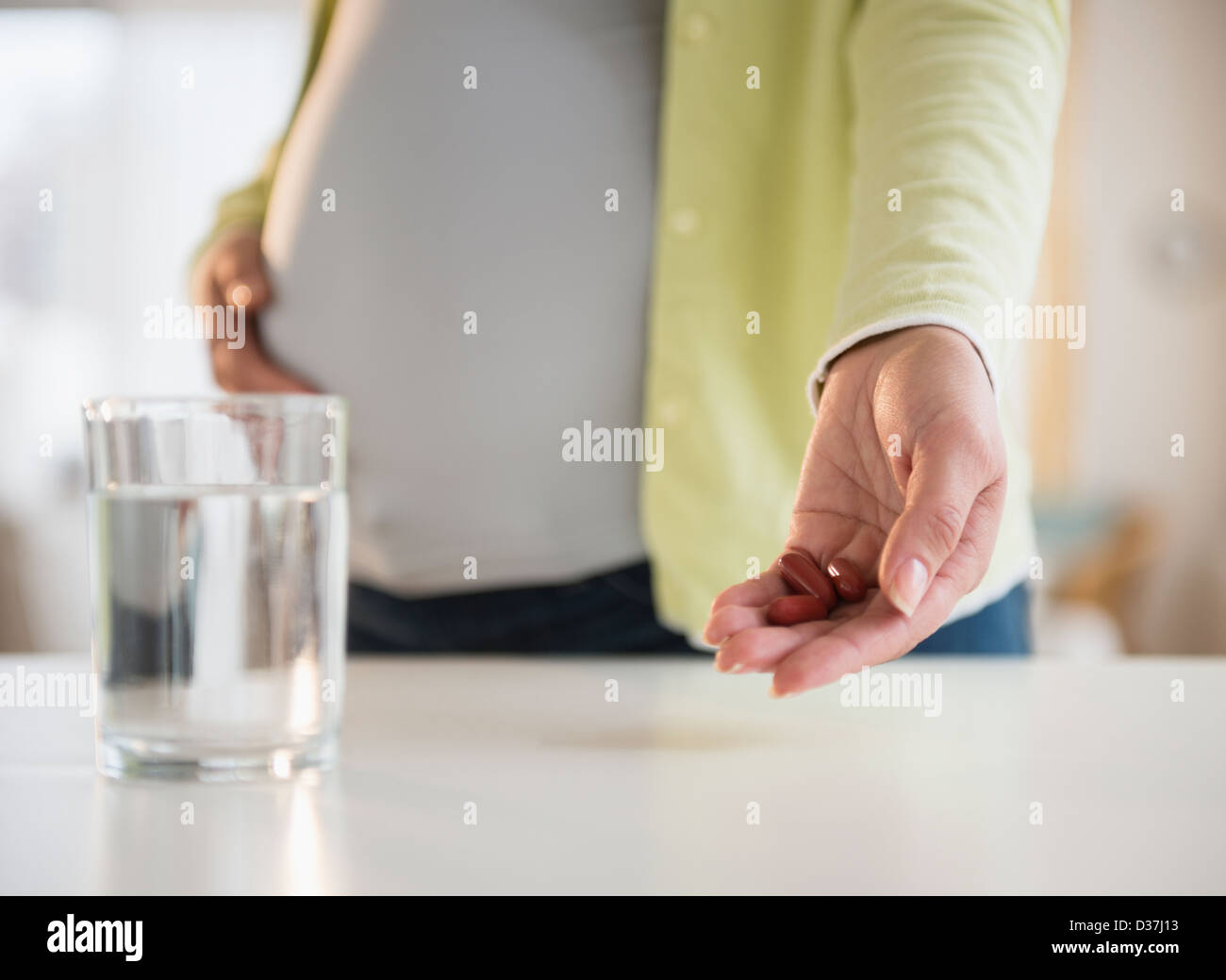 Schwangere Frau mit Medizin mit Glas Wasser vor Stockfoto