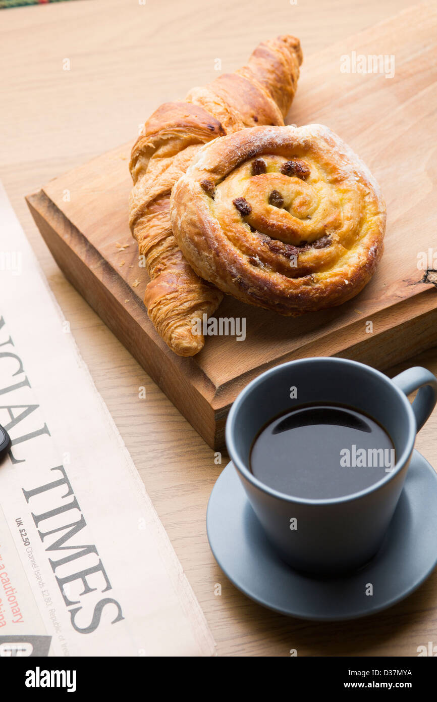 Frisches Gebäck Espresso und ein HTC One X + Handy mit einer Kopie der Financial Times Zeitung auf eine Holzoberfläche. Stockfoto