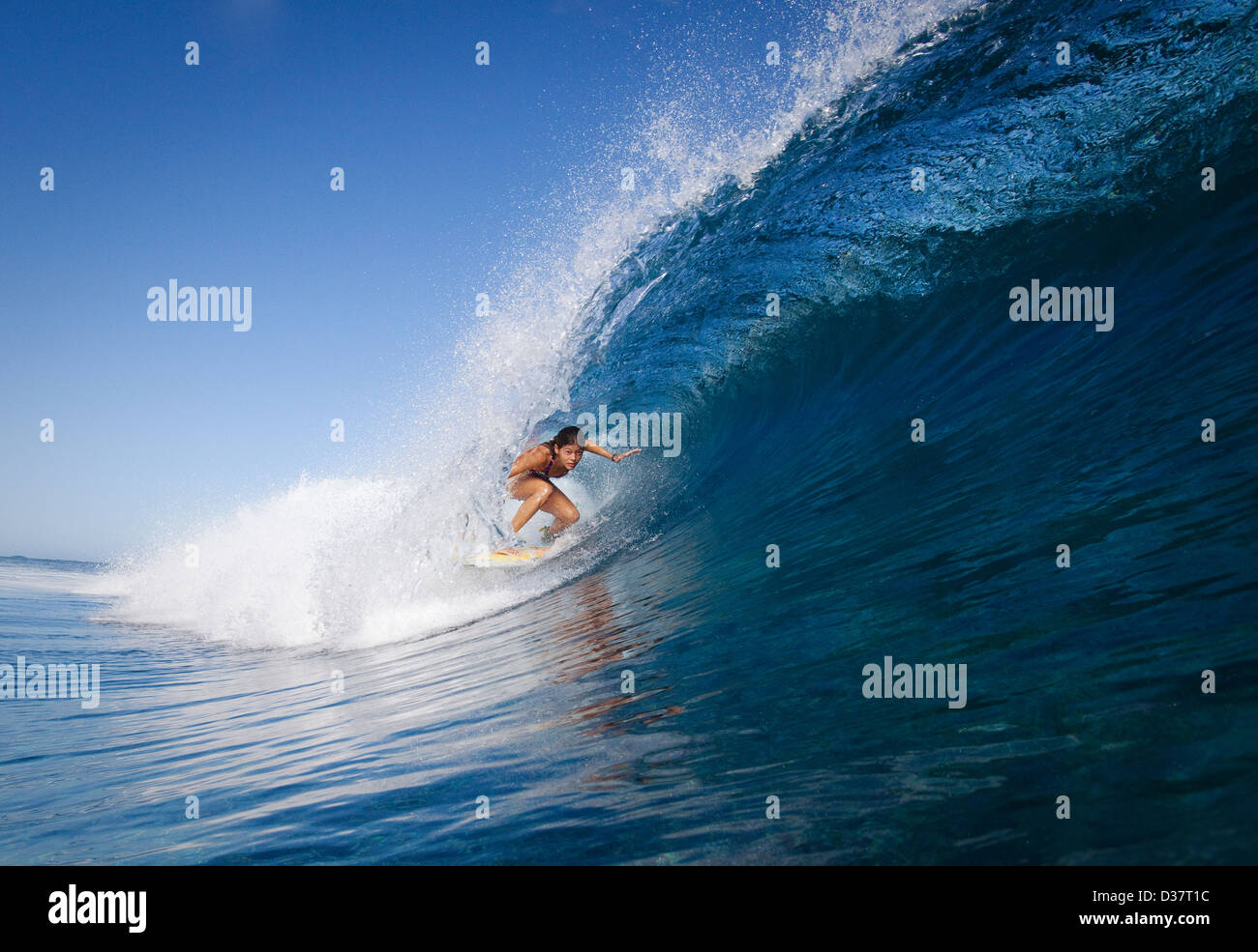Frau im Kamm der Welle surfen Stockfoto
