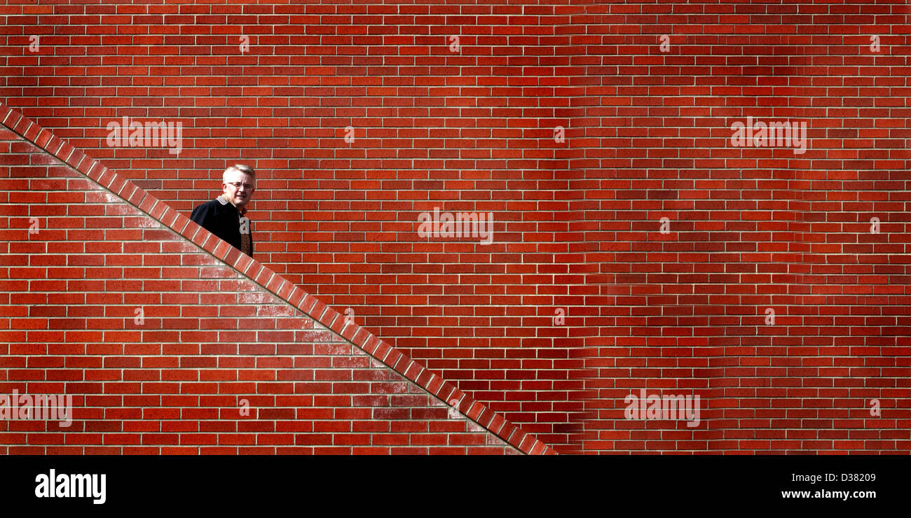 Mann, die Treppen hinunter mit Mauer im Hintergrund Stockfoto