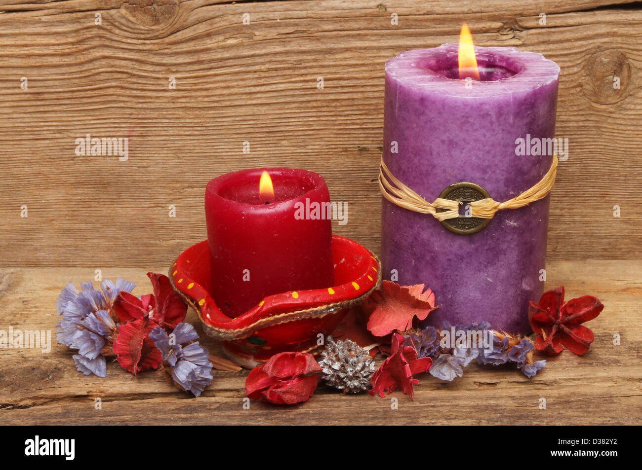 Rote und violette Kerzen mit Potpourri auf einem Hintergrund verwitterte alte Holz Stockfoto