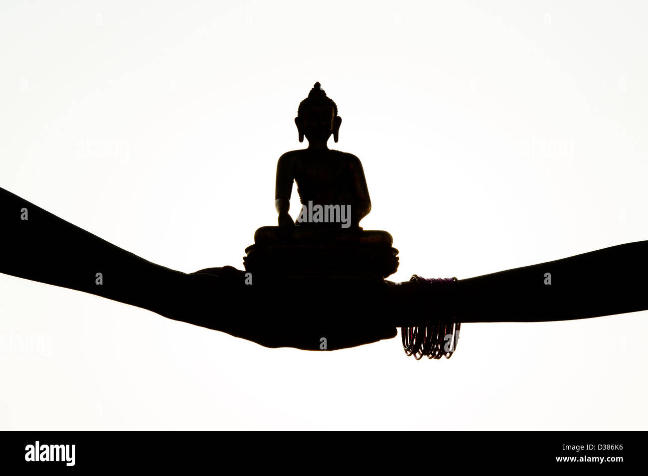 Indische Hände halten eine Buddha-Statue. Silhouette Stockfoto