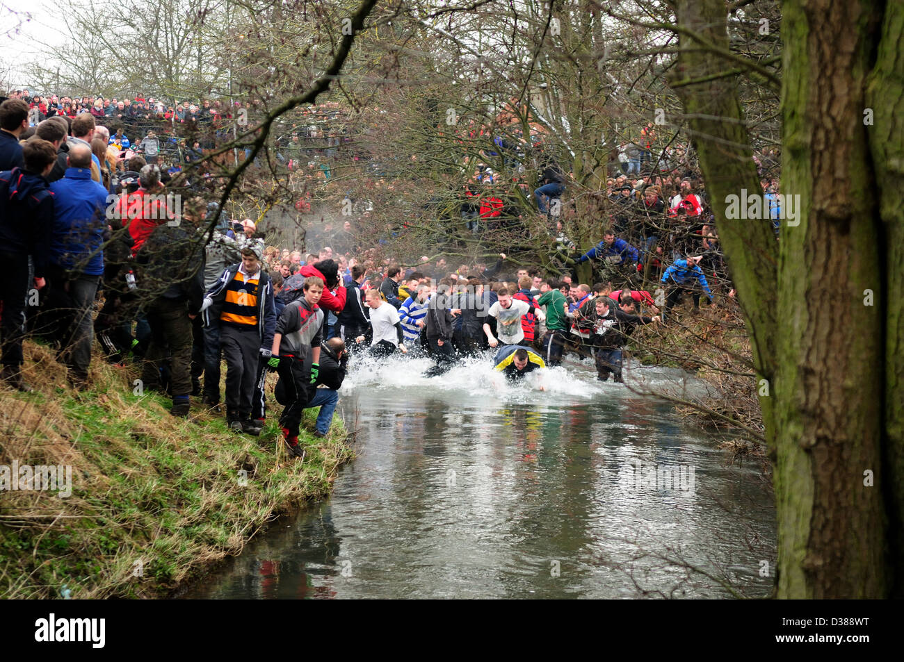 Ashbourne,Derbyshire.Shrovetide alten Fußball 2013.Play betritt den Henmore-Fluss. Stockfoto