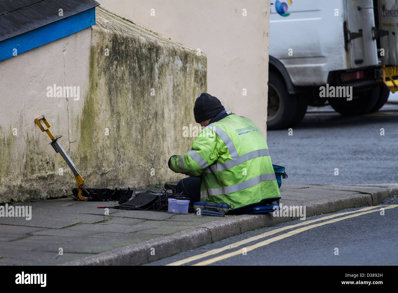 Mann bei der Arbeit durch Loch im Pflaster Stockfoto