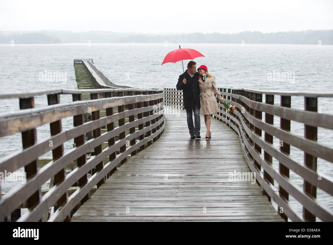 Paare, die auf Holzmole in Regen Stockfoto