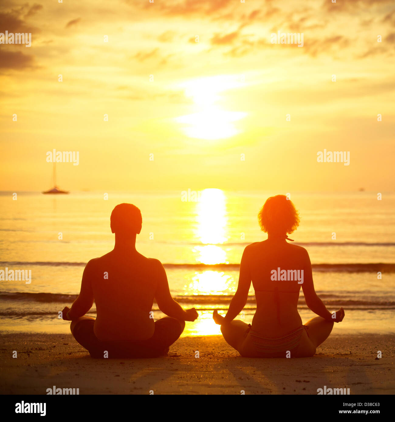 Junges Paar in einem Lotussitz meditieren am Strand bei Sonnenuntergang Stockfoto