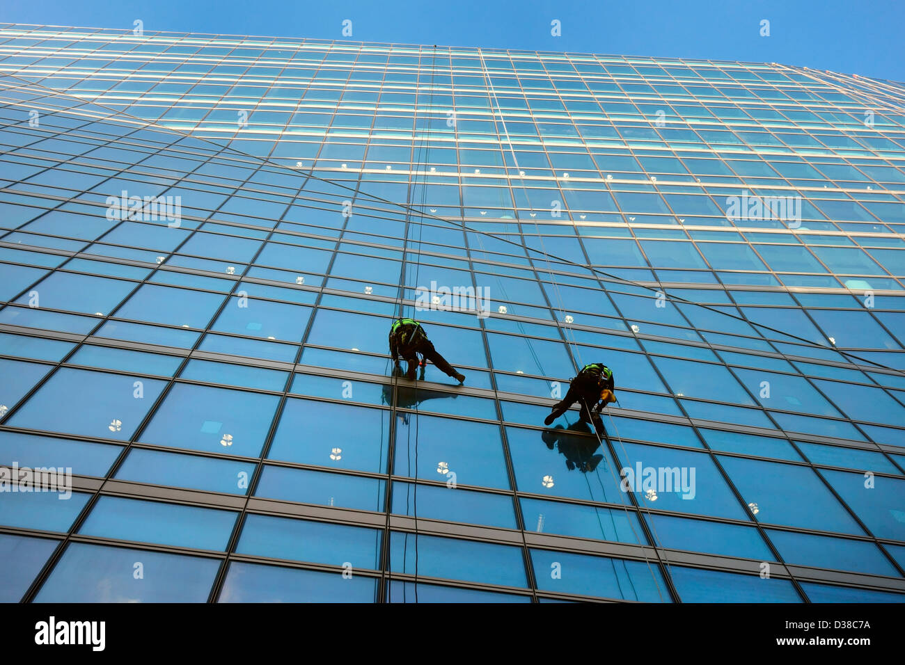 Zwei Männer Abseilen beim Fensterputzen von einem großen Glas-Bürogebäude Stockfoto