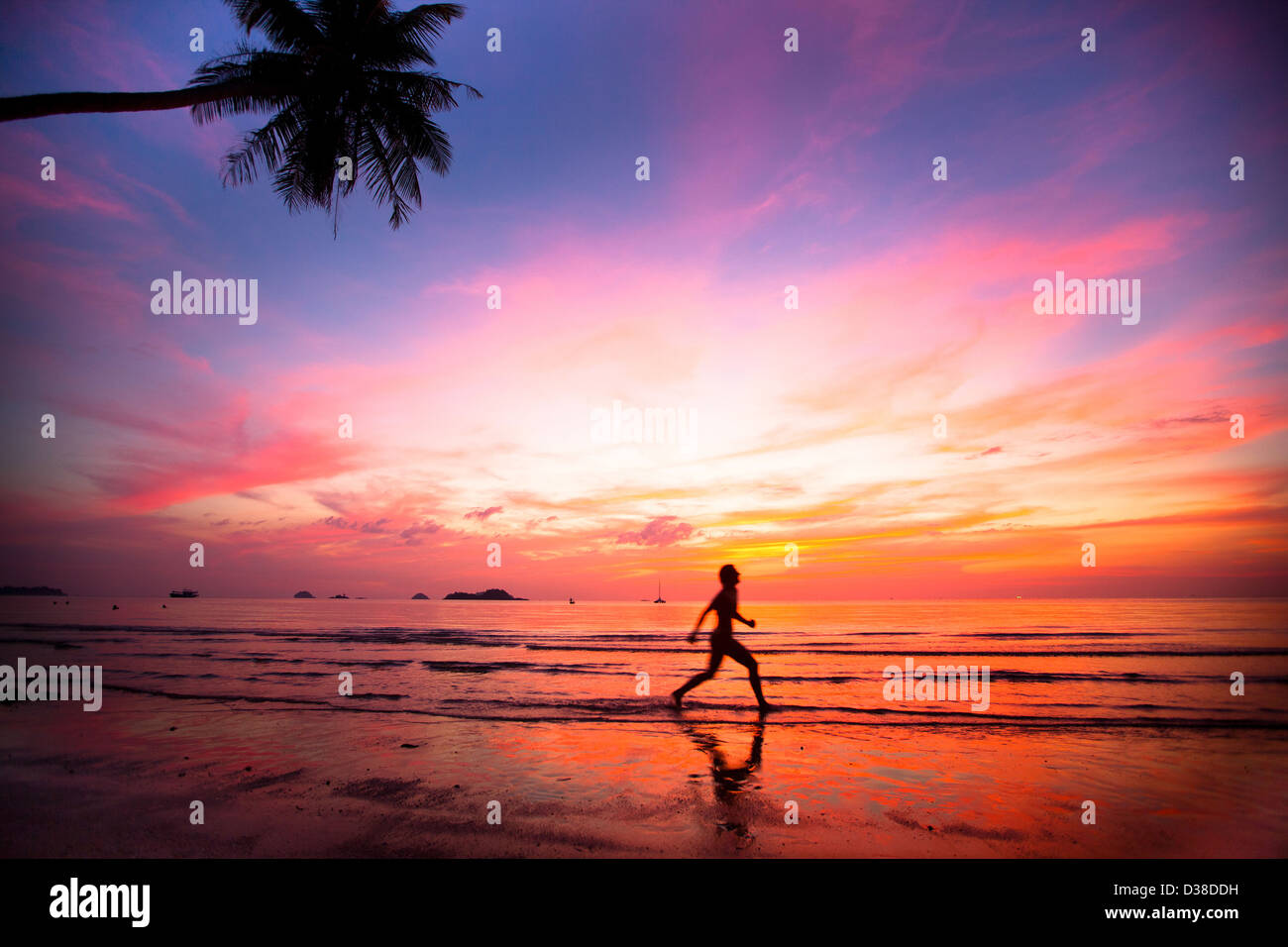 Sonnenuntergang mit Silhouetten von Mädchen am Strand jogger Stockfoto
