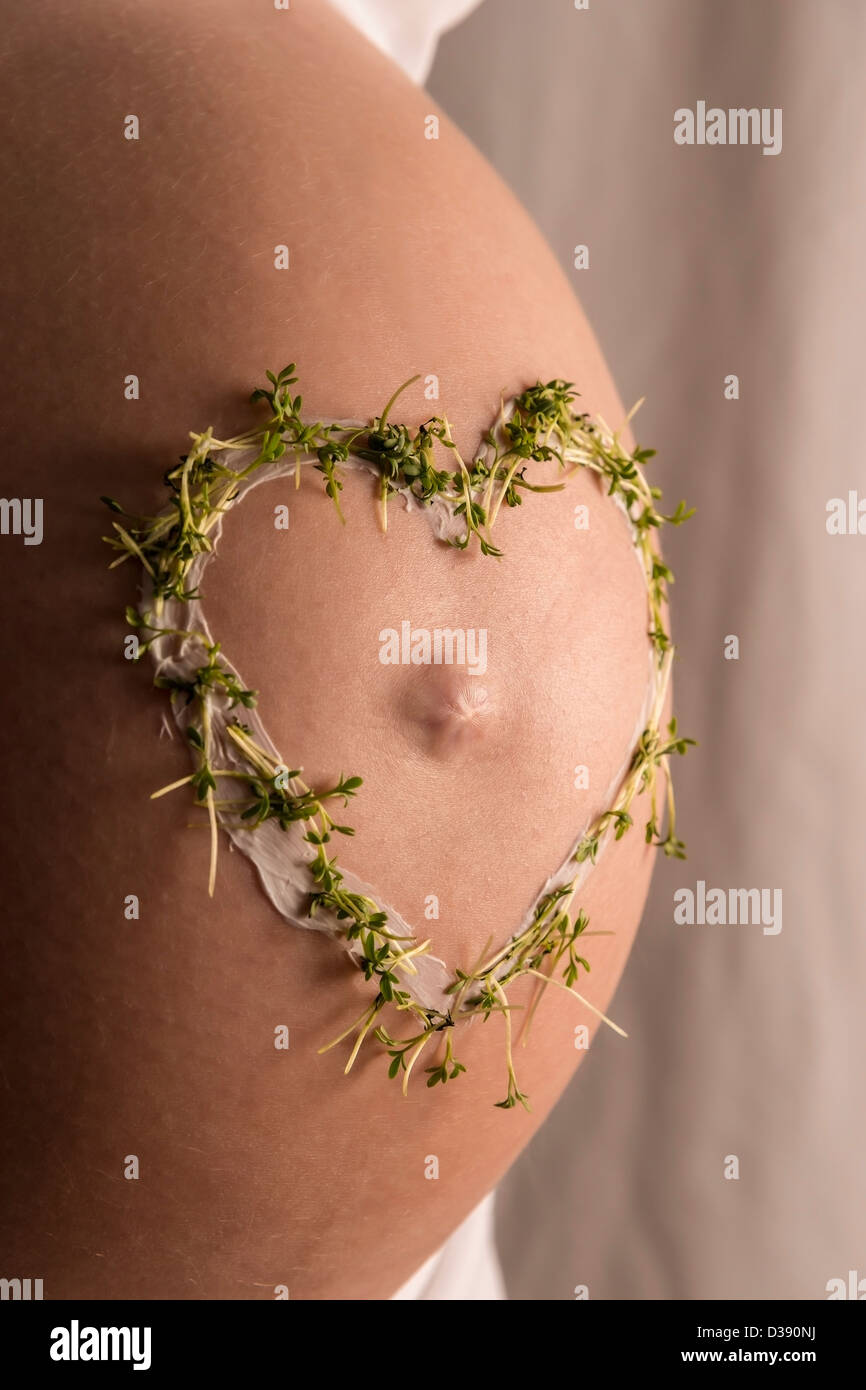 Nahaufnahme von junge Frau mit einem Kresse-Herz auf ihrem Baby-Bauch Stockfoto