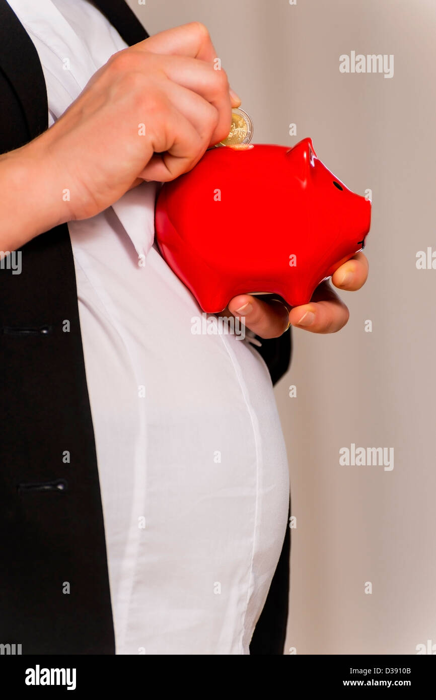 Schwanger Geschäftsfrau wirft zwei Euro im Sparschwein Stockfoto