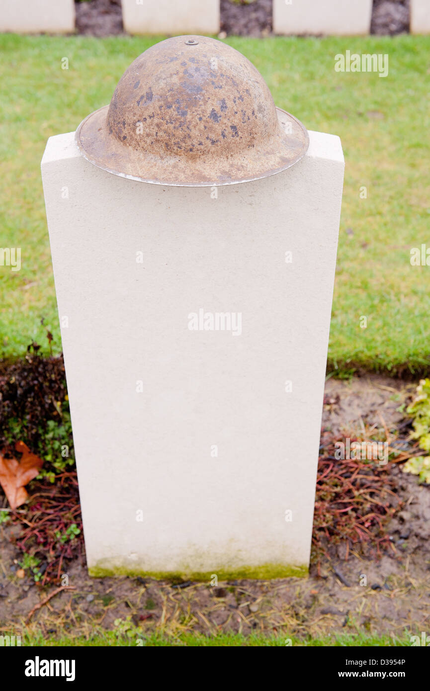 Leere Grabstein in einem Commonwealth Soldatenfriedhof mit einem britischen militärischen Helm auf der Oberseite platziert. Stockfoto