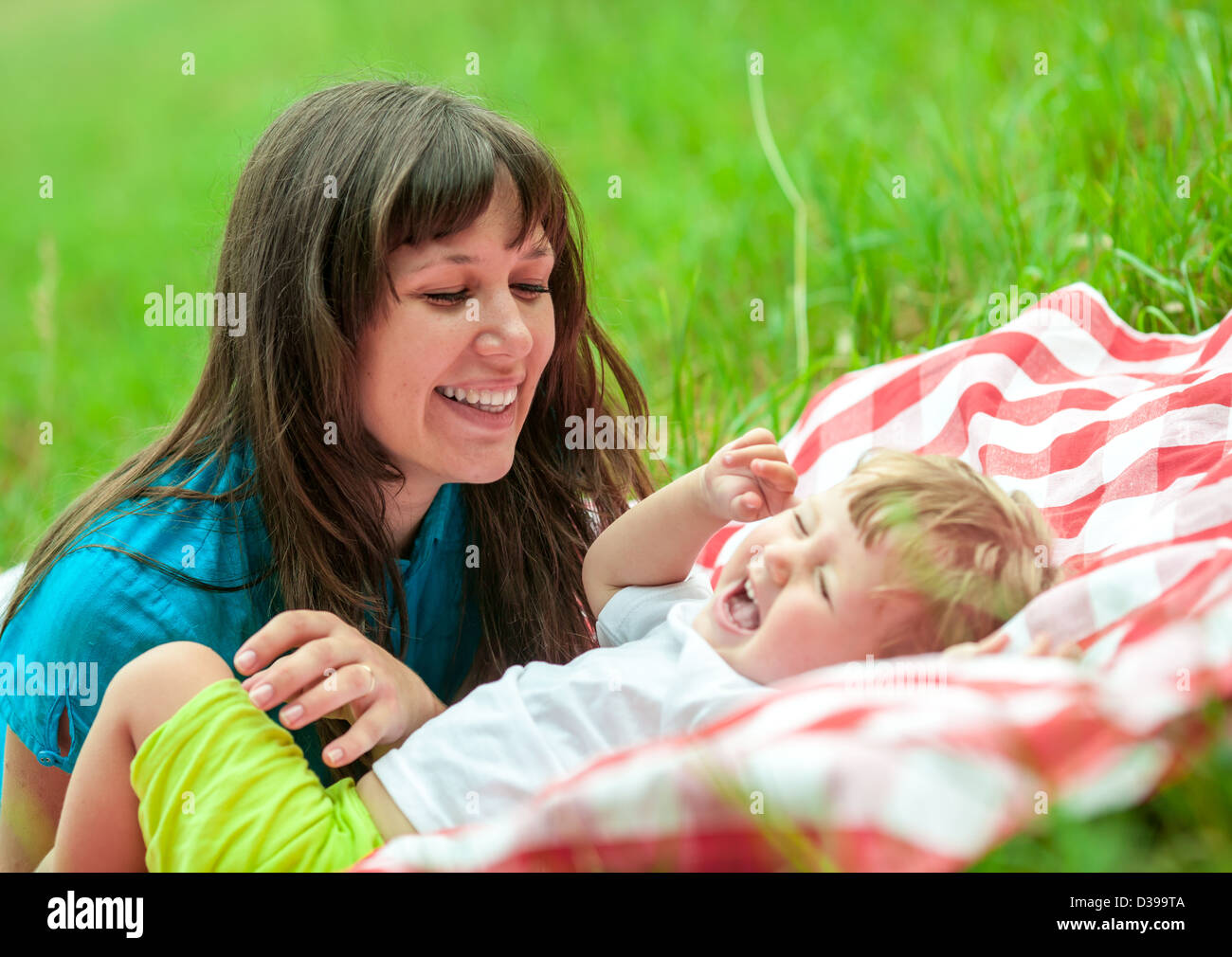 glückliche Mutter und Tochter haben Picknick im Freien auf dem grünen Rasen Stockfoto