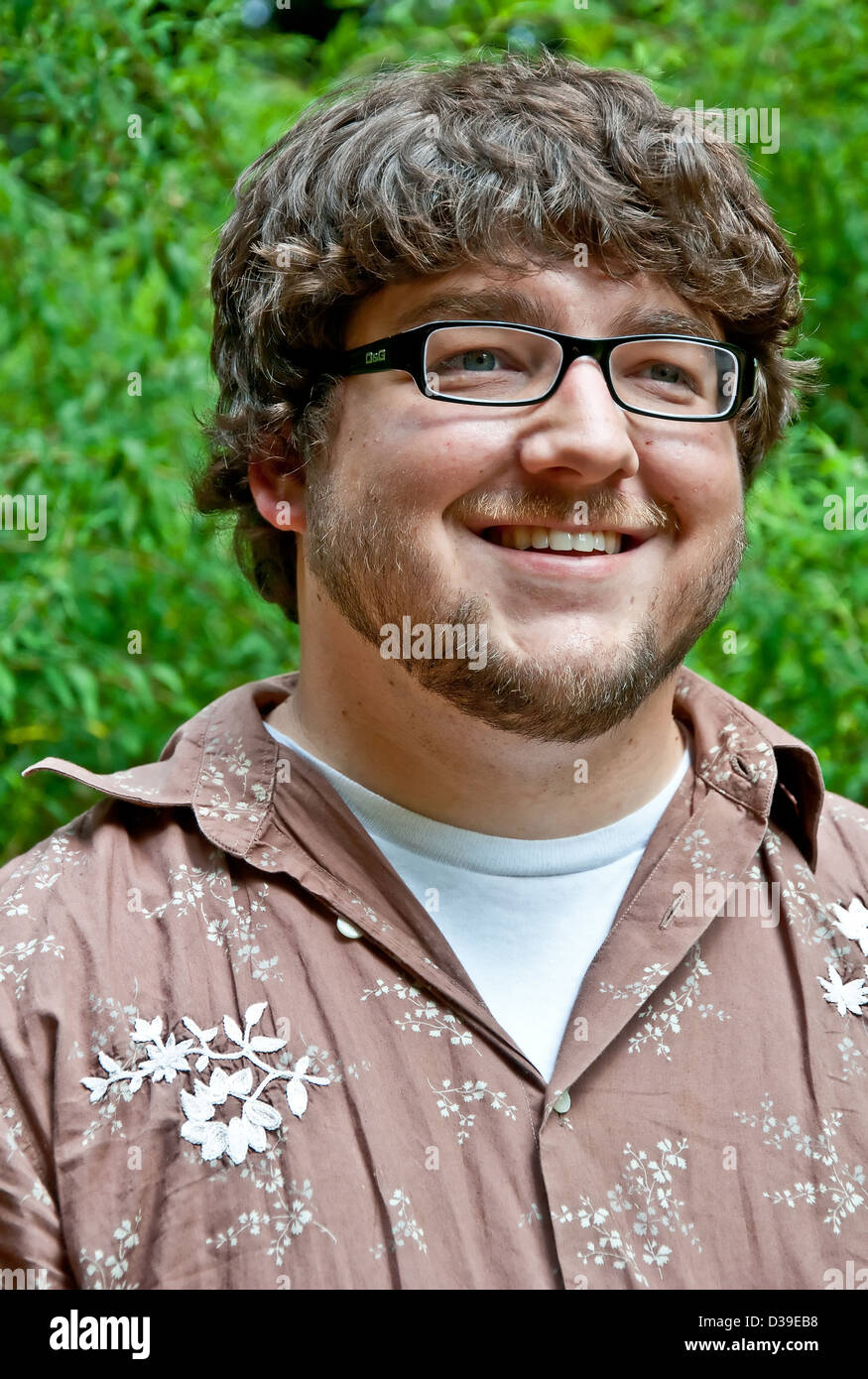 Kaukasisches junge Männchen ist in seinen frühen Zwanzigern in diesem Outdoor-Portrait. Er ist schwarz umrandeten Brille. Stockfoto