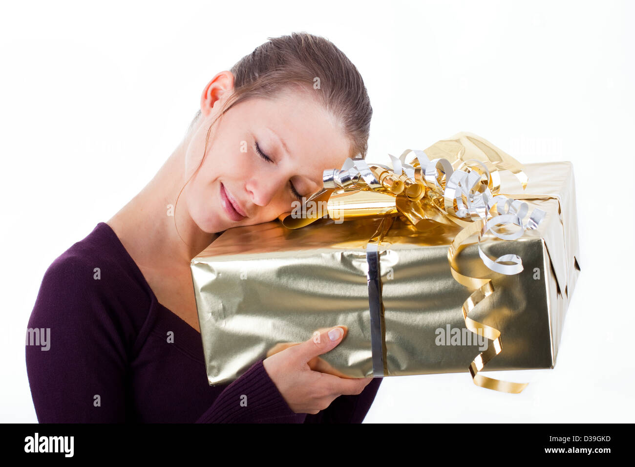 Attraktive Frau schmiegen sich um große, goldene Paket Stockfoto