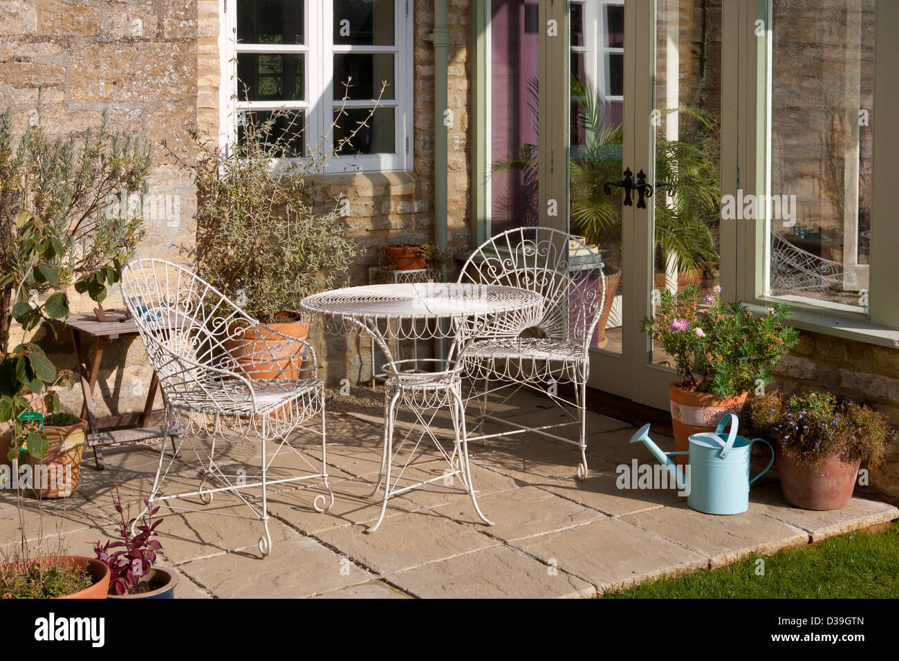 Metall-Stühle und Tisch auf der Terrasse Wintergarten im englischen Garten, Oxfordshire, England Stockfoto