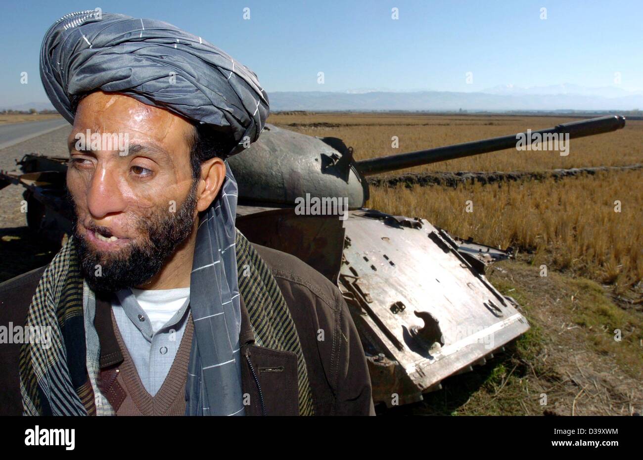 (Dpa) - eine afghanische Opfer von Krieg, der 40 Jahre alte Ex-Mudschaheddin Dadguhl Delawan, steht vor einer russischen Panzer außerhalb Kundus, Afghanistan, 27. November 2003. Er zerstört dieses Panzers zwölf Jahren im November 1991 mit einer Panzerfaust, bevor er durch einen anderen Panzer entdeckt wurde und schwere Gesicht erlitt Stockfoto