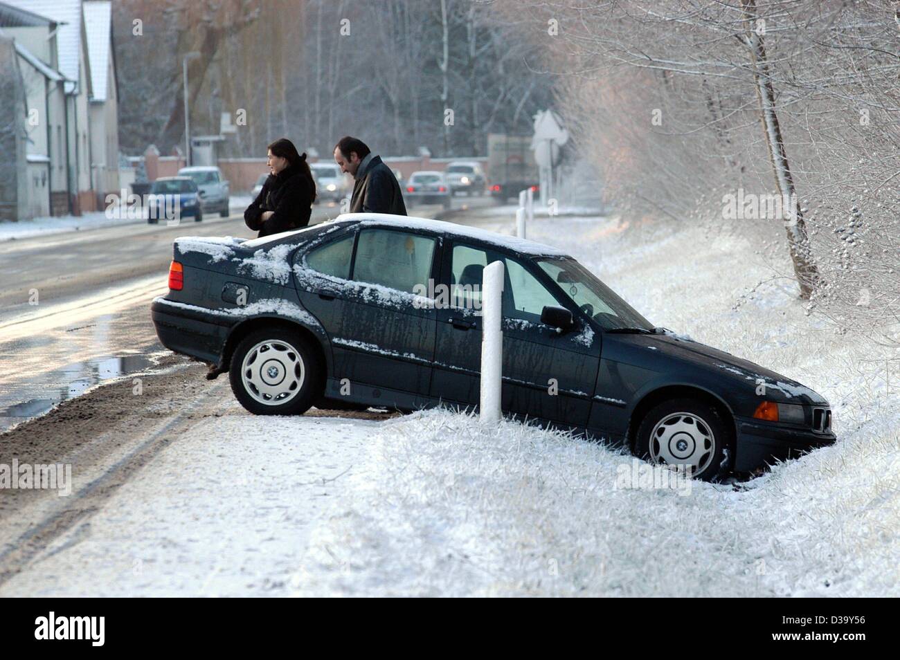 (Dpa) - stehen die Passagieren neben ihrem Auto, das von der Straße auf der B3-Autobahn in Egelsbach, Deutschland, 23. Dezember 2003 rutschte hat. Schnee und Glatteis führten zu Chaos und Unfälle in ganz Deutschland. Stockfoto