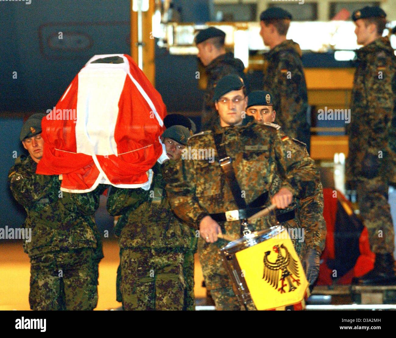 (Dpa) - ein Schlagzeuger März vor Soldaten der ISAF (International Security Assistance Force), die einen dänischen Soldaten Sarg bedeckt mit der Nationalflagge im Rahmen einer Feierstunde in Köln, Deutschland, 9. März 2002 durchzuführen. Zwei deutsche und drei dänische ISAF-Soldaten starben bei explodierender Munition Stockfoto