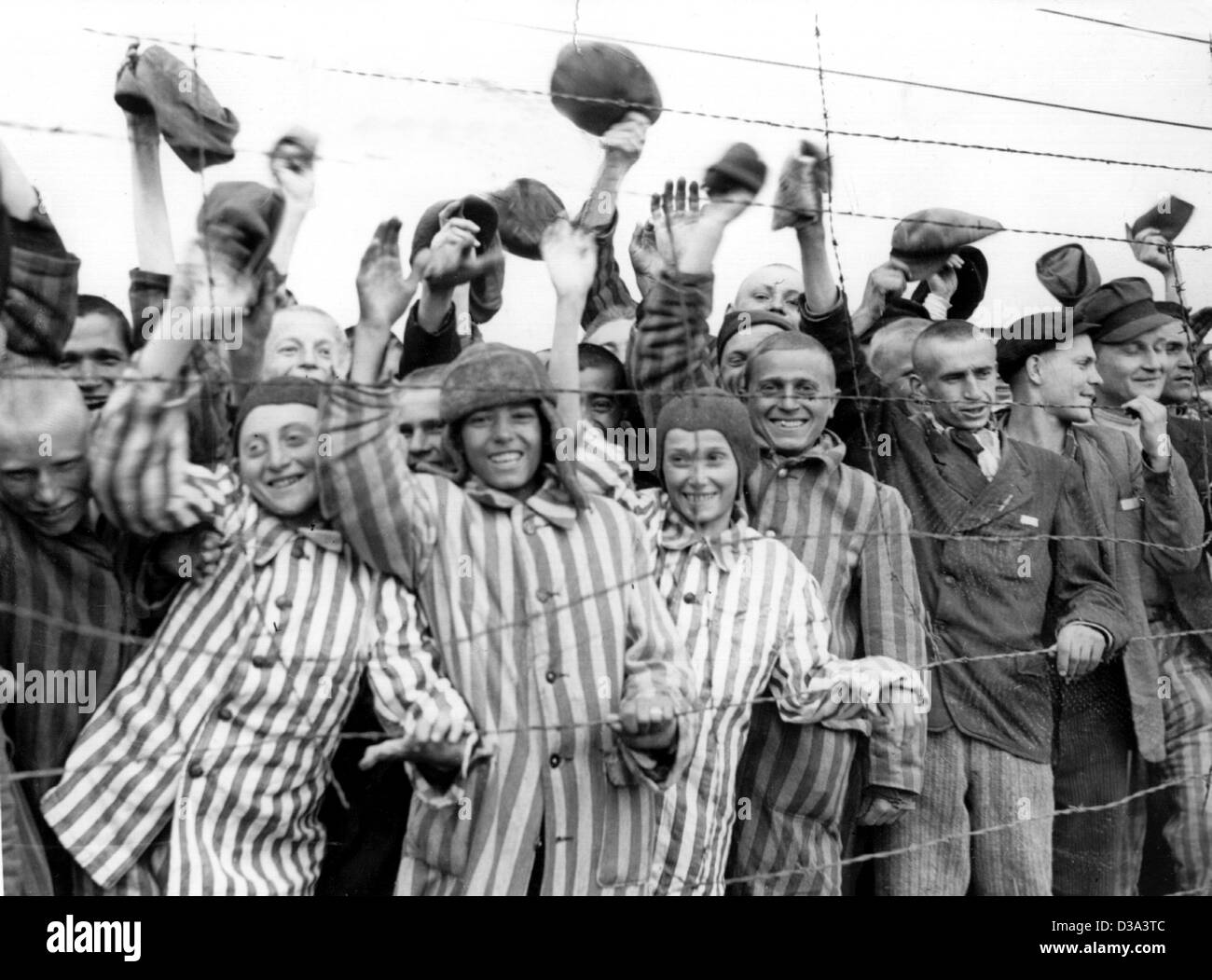 (Dpa-Dateien) - Häftlinge des Konzentrationslagers jubilate und Welle in Richtung ihre Befreier als US-Truppen in das Konzentrationslager in Dachau, Deutschland, 30. April 1945 ankommen. Dachau war das erste nationalsozialistische Konzentrationslager, gegründet am 22. März 1933, nur wenige Wochen, nachdem Hitler in p gekommen Stockfoto