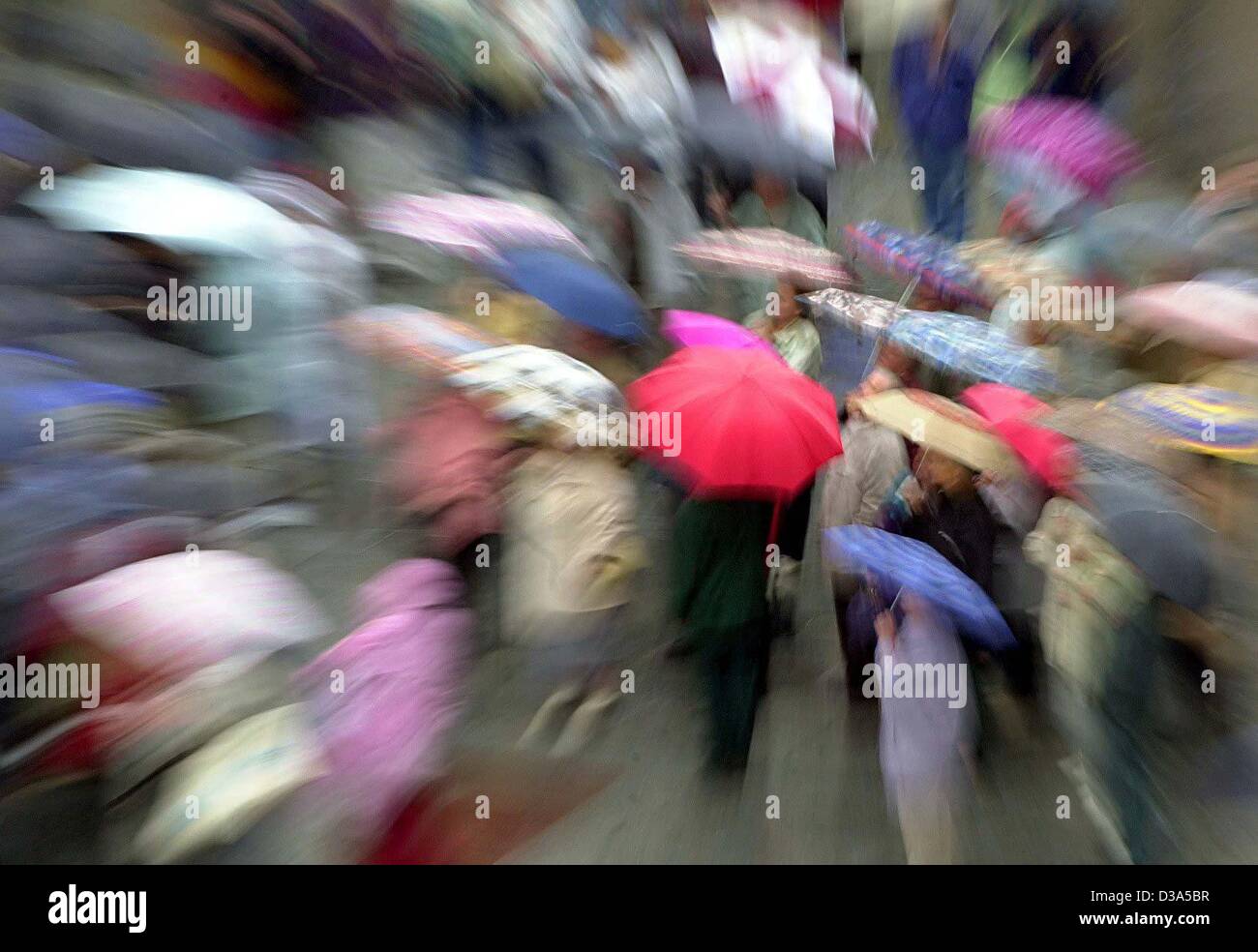 (Dpa) - eine Menge von Menschen, die Sonnenschirme, verzogen durch einen Zoom-Effekt, zu Fuß an einem regnerischen Tag durch die Stadt München, 28. Mai 2002. Stockfoto