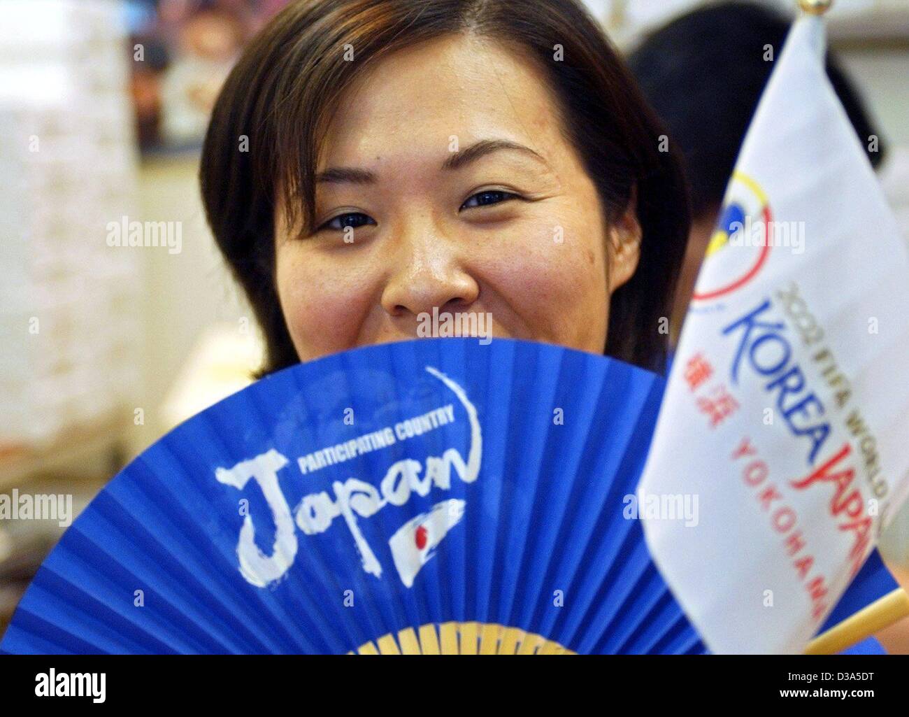 (Dpa) - eine Verkäuferin ein WM-Souvenir-Shop am Bahnhof Shin-Yokohama, Japan, lächelt hinter einem blauen Ventilator und ein kleines Fähnchen, das Japan und der Republik Korea als Gastgeber des FIFA World Cup, 30. Mai 2002 markieren. Am nächsten Tag eröffnete Fußball-Wettbewerb 2002 in Seoul, Korea. Stockfoto