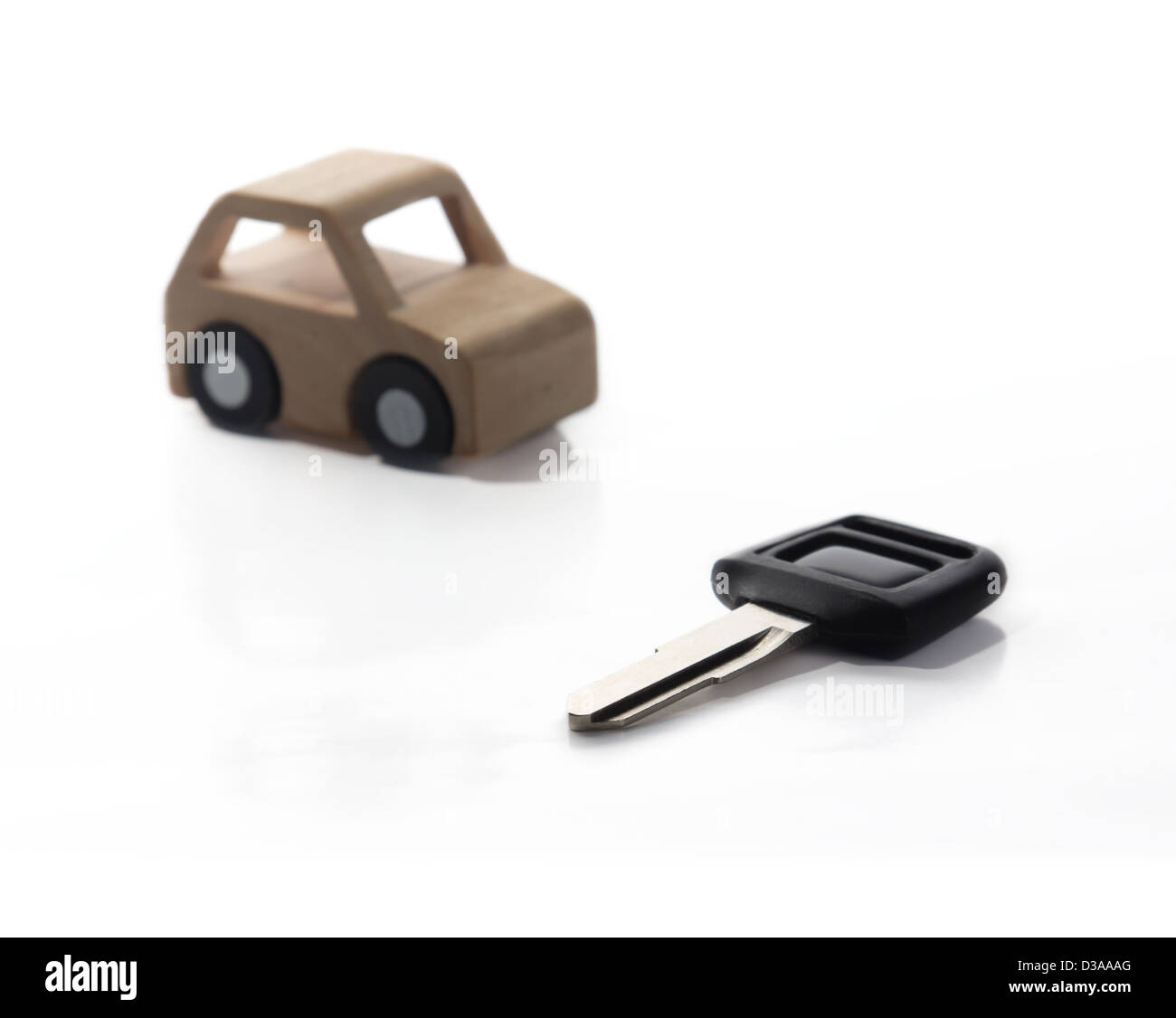 Schlüssel und Auto aus Holz auf weißem Hintergrund. Stockfoto