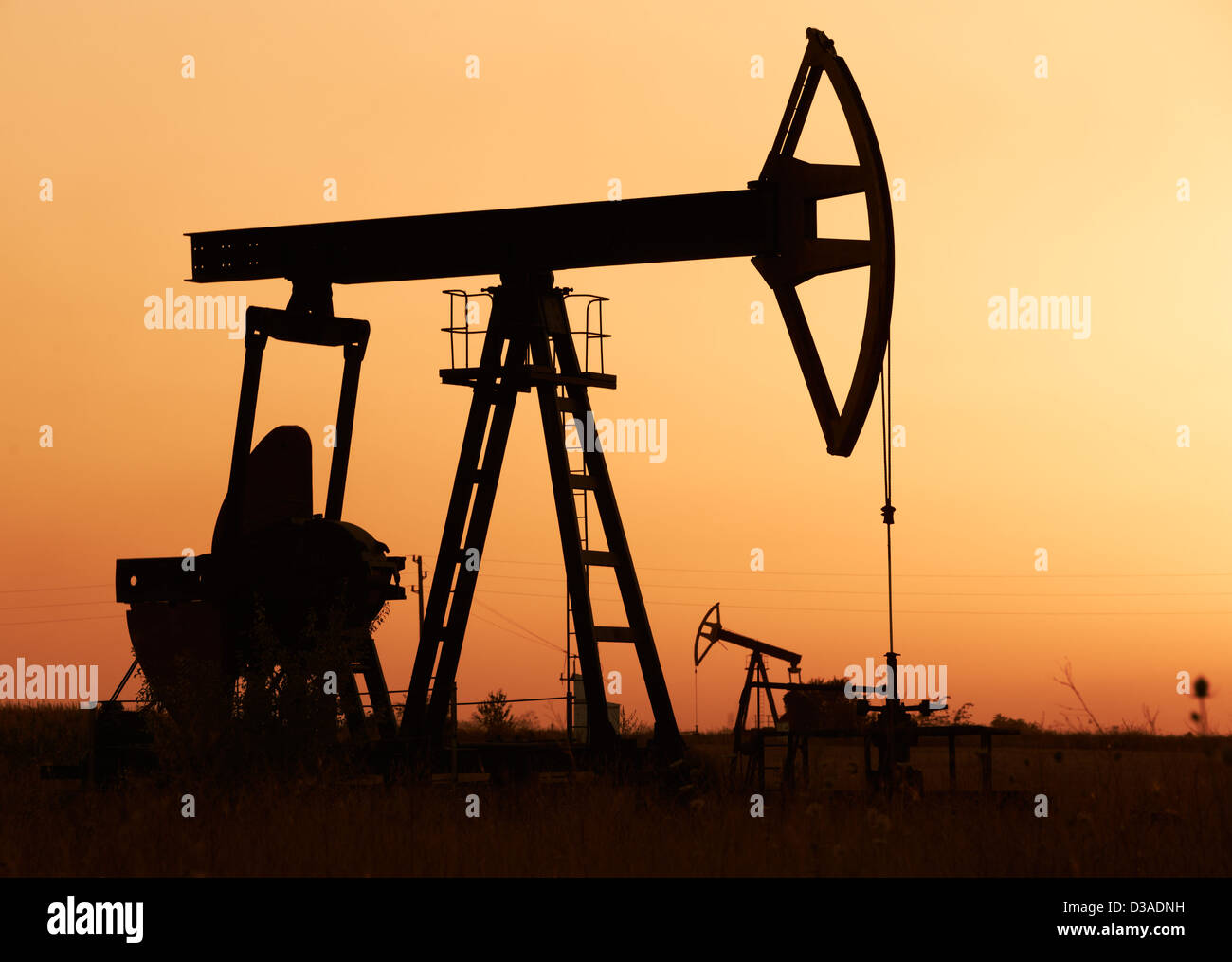 Öl Pumpen Silhuettes Betrieb bei Sonnenuntergang Stockfoto